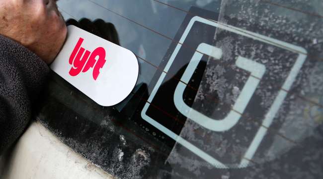 Driver putting Lyft sticker car next to Uber sticker