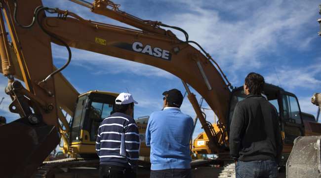 Customers inspect heavy digging machinery at a 2012 Ritchie Bros. auction