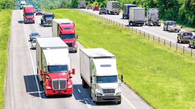 Tractor-trailers drive along a highway