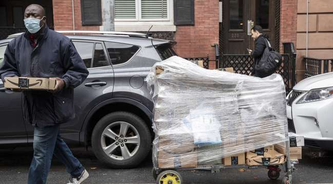 A worker carries Amazon packages during a delivery in New York.