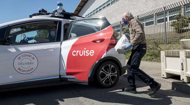 A volunteer loads bags of food into a Cruise LLC self-driving training car