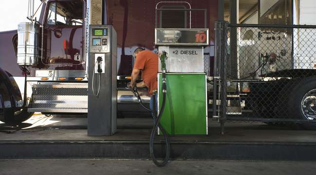 Truck driver pumps diesel fuel into purple truck
