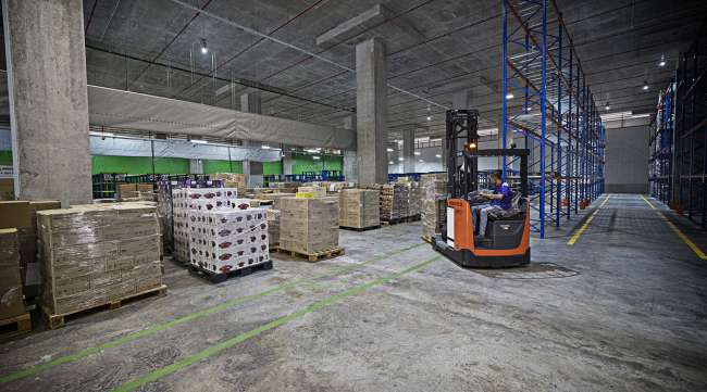 Warehouse inventory is moved with a forklift.