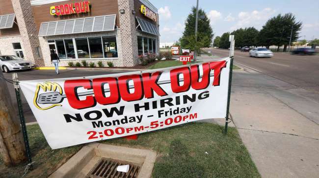 Cars drive by a help wanted sign at a Cook Out restaurant in Jackson, Miss.