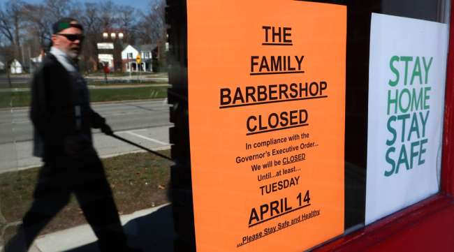 A pedestrian walks by a closed barbershop in Michigan on April 2.