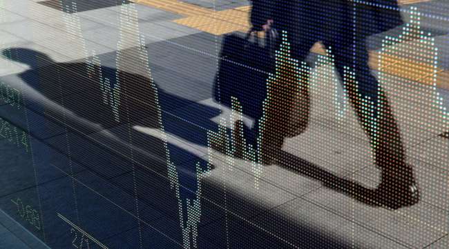 A businessman is reflected on an electronic stock board in Tokyo, Japan.
