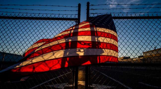The shadow of a lock glows through an American flag on a gate at the General Motors Flint Assembly Plant in September 2019, during a UAW strike.