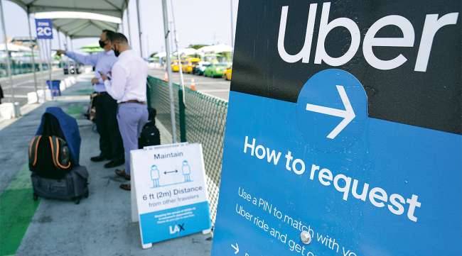 California travelers request an Uber ride. (Damian Dovarganes/Associated Press)