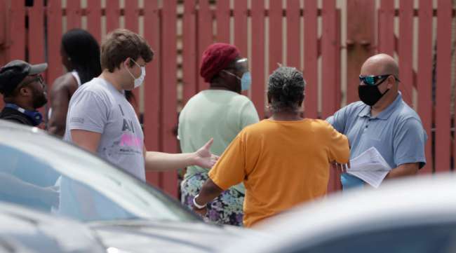 A worker, right, hands out paper unemployment applications in Hialeah, Fla., on April 7.
