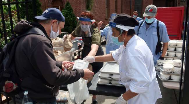 Ginger Pierce, center, and Pablo Guzman, right, hand out food at the Holy Apostle Soup Kitchen in New York on May 19.