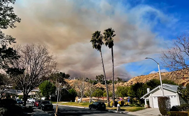 Neighborhood with smoke in sky in background