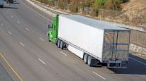 Green tractor drives down highway