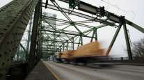 Blurred truck drives over steel bridge