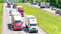 Tractor-trailers drive along a highway