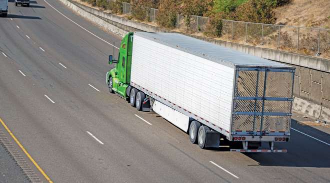 Green tractor drives down highway