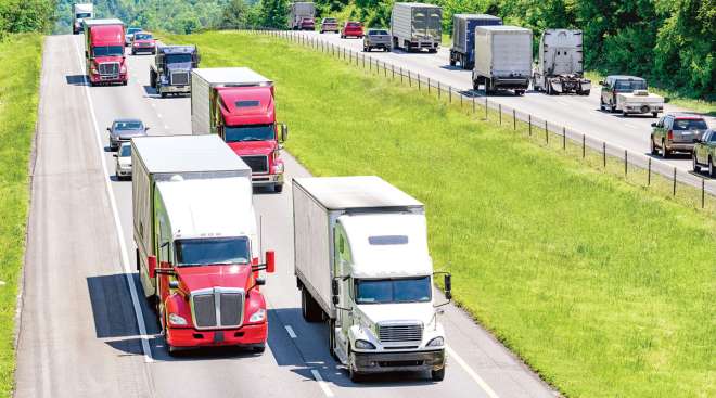 Tractor-trailers drive along a highway